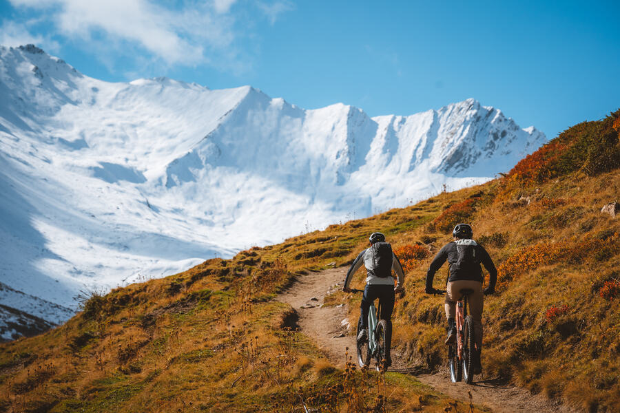Riders climbing a singletrack under the snow faces